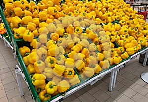 Yellow peppers in green boxes are for sale in a mall in the department of vegetables and fruits