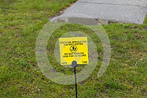 Yellow pesticide application sign on resedential front lawn