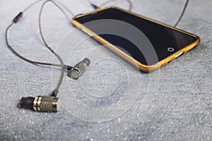 Yellow phone with headphones on a shiny silver background