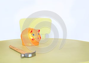 Yellow piggy bank and hammer on the table on white background. Saving money concept