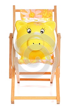 Yellow piggybank on deckchair