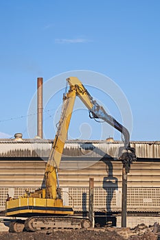 Yellow Pile drilling crawler crane working to install foundation near the old factory building in industrial construction site