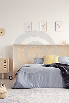 Yellow pillow and blanket on blue bed in bright bedroom interior