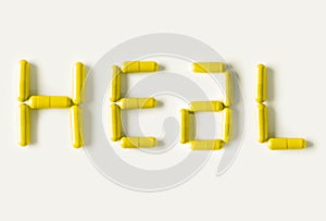 Yellow Pills capsules in shape of word Heal. Life concept isolated.