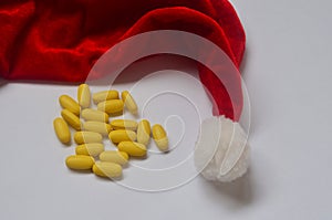 Yellow pills. Homeopathy, treatment, medicine. Pills, capsules. Christmas, decorations, santa claus hat. Drugs, virus, quarantine.