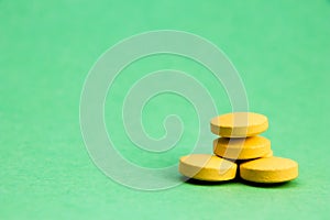 Yellow pills isolated on green background with clipping path. Medicine and pharmacy concept