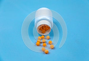 Yellow pills and plastic white bottle. Blue background with copy space for text