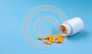 Yellow pills and plastic white bottle. Blue background with copy space for text