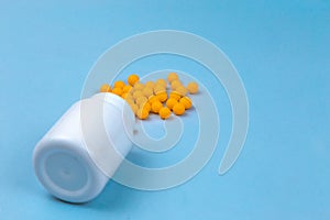 Yellow pills and plastic white bottle. Blue background with copy space for text