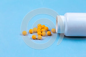 Yellow pills and plastic white bottle. Blue background with copy space for text