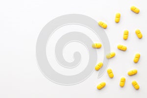 Yellow pills scattered on a white background.