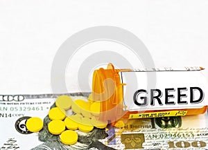 Yellow pills spill on one hundred dollar bill from bottle with greed written on it