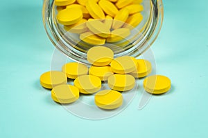 yellow pills spilling out of a toppled pill bottle