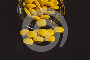 yellow pills spilling out of a toppled pill bottle