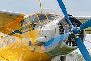 Yellow pilots cabin and engine with blue four blade propeller of soviet aircraft biplane Antonov AN-2 closeup