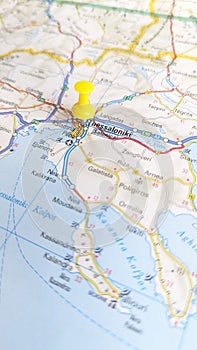 A yellow pin stuck in Thessaloniki on a map of Greece portrait