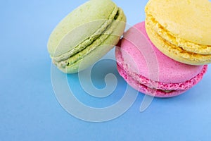 Yellow, pink and green macarons in the corner on blue background.