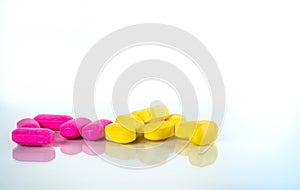 Yellow and pink oval tablet pills with shadows on white background with copy space for text. Mild to moderate pain management.