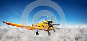 Yellow plane flying in the sky between clouds