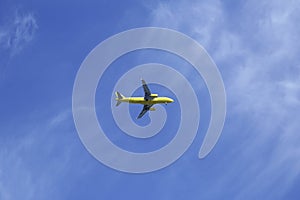 Yellow plane with landing gear down in blue sky with copy space for text and image