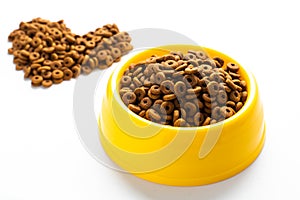 Yellow plastic bowl full with dry dog food isolated on white background. Top view grain pet food with copy space of text design.