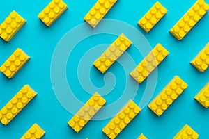 Yellow plastic building blocks on turquoise blue background with copy space