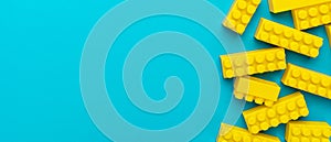 Yellow plastic building blocks on turquoise blue background with copy space