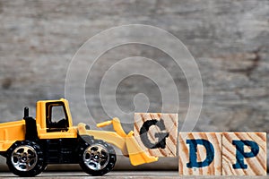 Yellow plastic bulldozer hold letter G to complete word GDP photo
