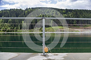 Yellow plastic buoy attached to a metal fence on the bank of a lake with green water