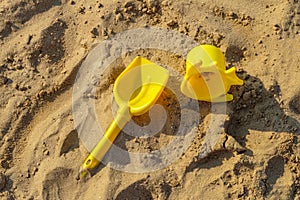 Yellow plastic childrens toys on the sand