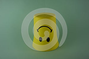 A yellow plastic cup with a smiling face, so it is very popular with children. Blue Background. Kids toys, kid friendly
