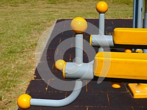 Yellow plastic exercise equipment detail in park. plastic grip on grey bent steel pipe frame.