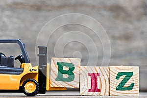 Yellow plastic forklift hold letter B to complete word biz & x28;Abbreviation of business& x29;