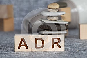 Yellow plastic forklift hold letter A to complete word ADR Abbreviation of Adverse drug reaction on wood background