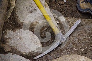 A plastic-handled pick leaning against a wall during work at an archaeological excavation