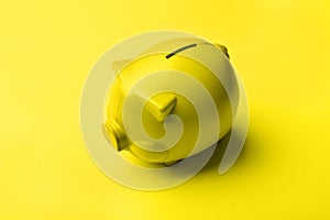 Yellow plastic piggy bank on yellow background