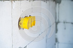 Yellow plastic recessed sockets, installation box for a socket in an aerated concrete block wall