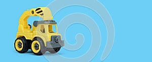 Yellow plastic truck toy isolated on blue background. construction vechicle truck.