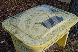 Yellow Plastic Winter Grit Sand Box Covered in Snow Standing by Icy Pavement