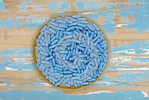 Yellow plate full of blue medicine capsules representing drug overdose