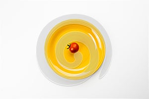 Yellow plate with red tomato, top view