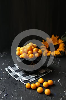 Yellow plums on the black background. Ingredients for a jam. Food photography. Vertical image. Yellow sunflower, Autumn