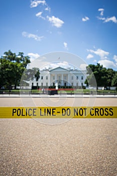 Yellow Police line - do not cross sign in the park with a white building in the background