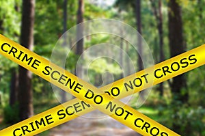 Yellow police tape with sign text: crime scene do not cross on scary forest background. A crime was committed in a forest area,