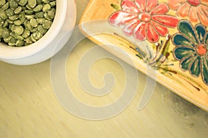 yellow porcelain tablemat and dried pease on a pastel green back
