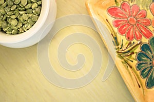 yellow porcelain tablemat and dried pease on a pastel green back