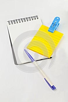 Yellow post note, empty white note, pen and blue clip