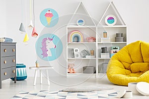 Yellow pouf in colorful child`s room interior with lamps and pos