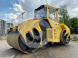 Yellow powerful large new modern road roller for asphalt paving and road repair at construction site. Construction machinery