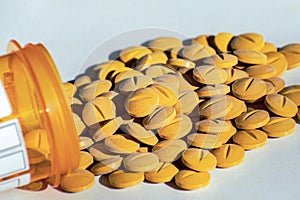 Yellow prescription pills spilled onto a table. Concept of opioid addiction and healthcare industry